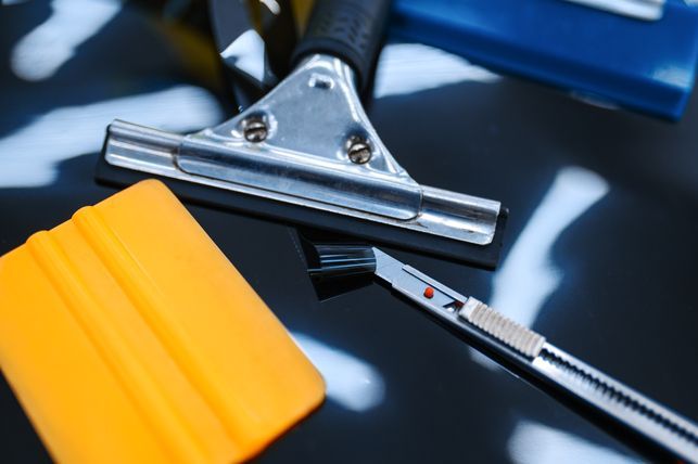 Tools for applying window film, including a squeegee, utility knife, and applicators.