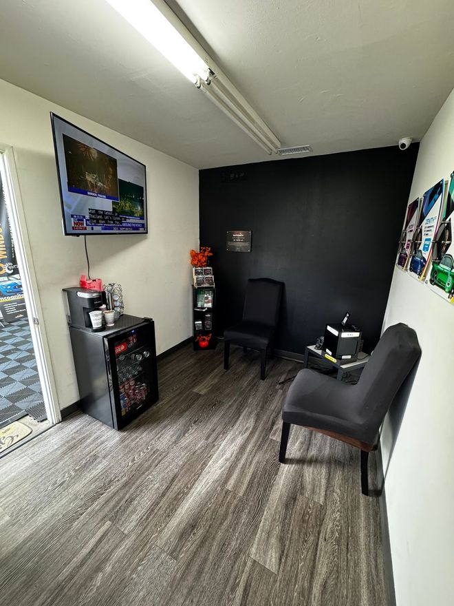 Waiting area with TV, black accent wall, chairs, and patterned flooring.