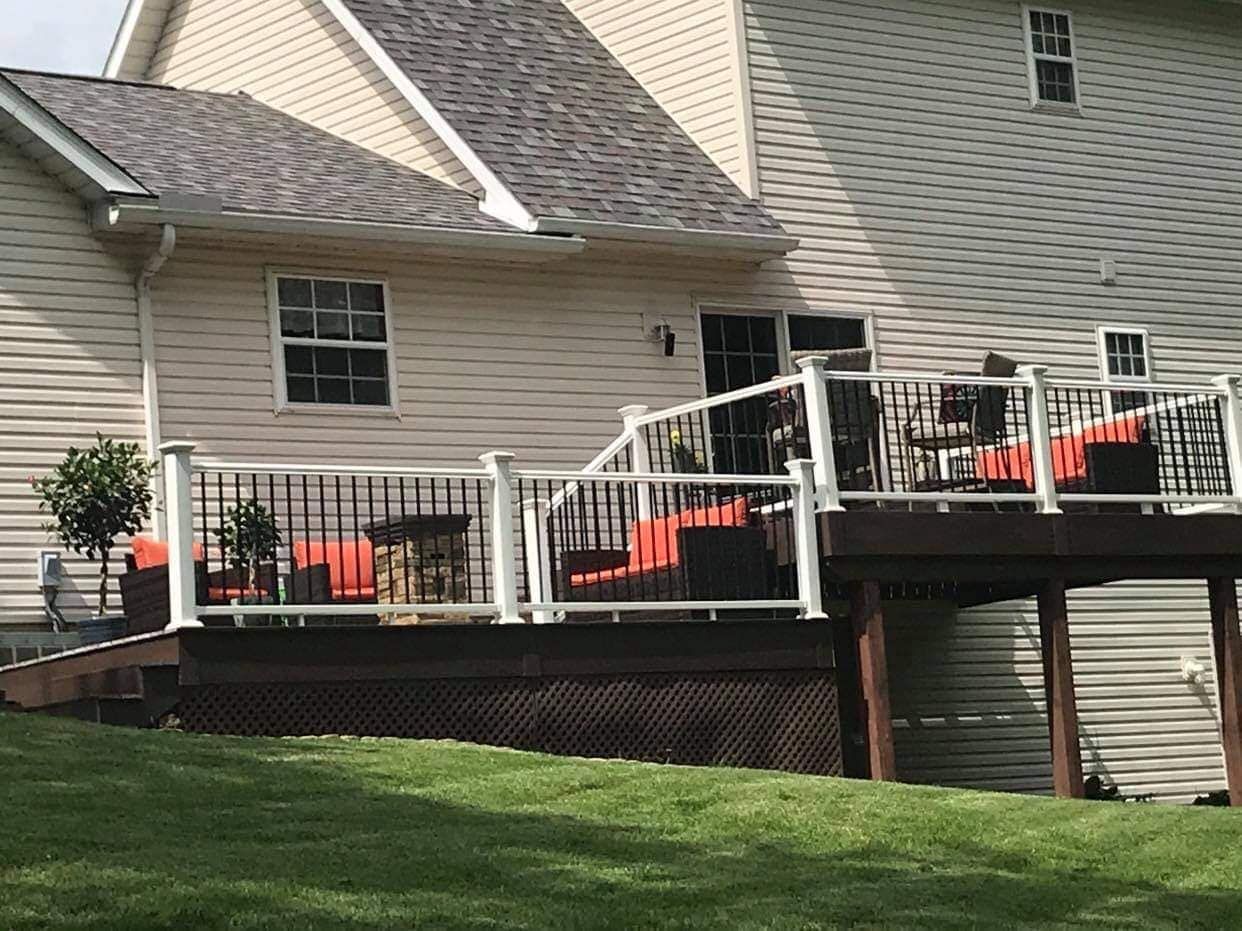 Backyard deck with brown furniture, overlooking a grassy lawn. The house has beige siding.