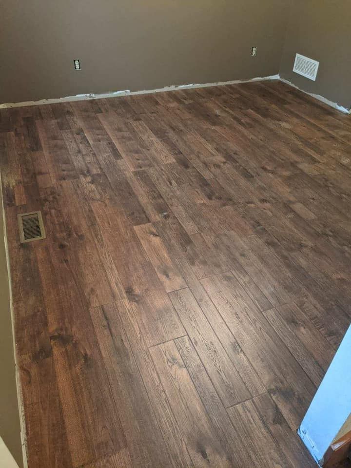 Newly installed wood-look laminate flooring in a room with brown walls and white trim.