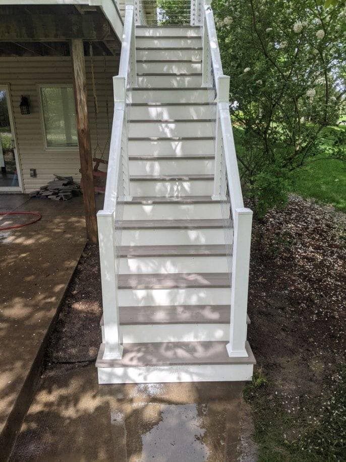 Outdoor staircase with white risers, gray treads, and white posts.