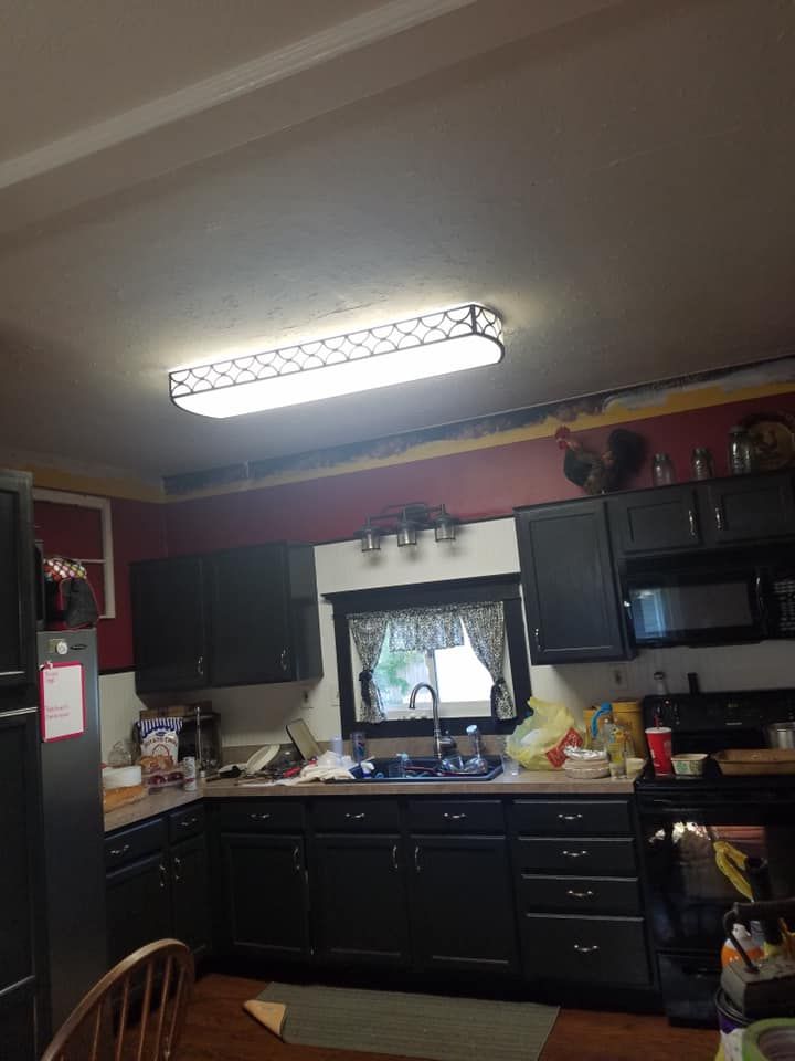 Kitchen with dark cabinets, a window above the sink, and a rectangular light fixture on the ceiling.