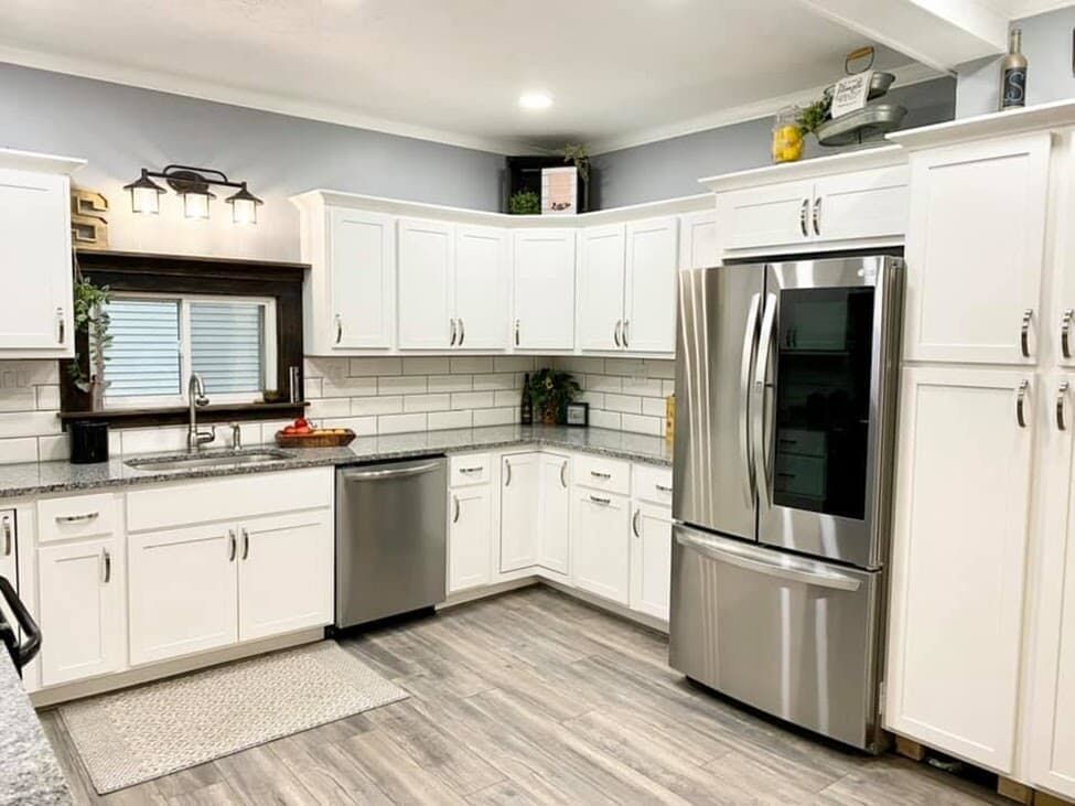 White kitchen with stainless steel appliances, white cabinets, and gray countertop.