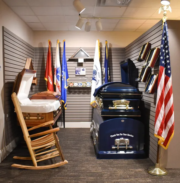A room with a rocking chair a coffin and an american flag
