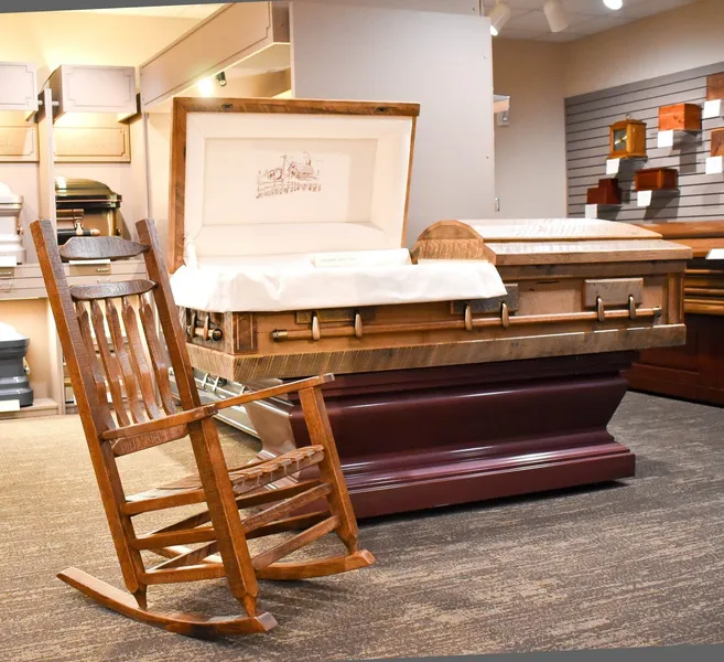 A rocking chair sits next to a coffin in a room