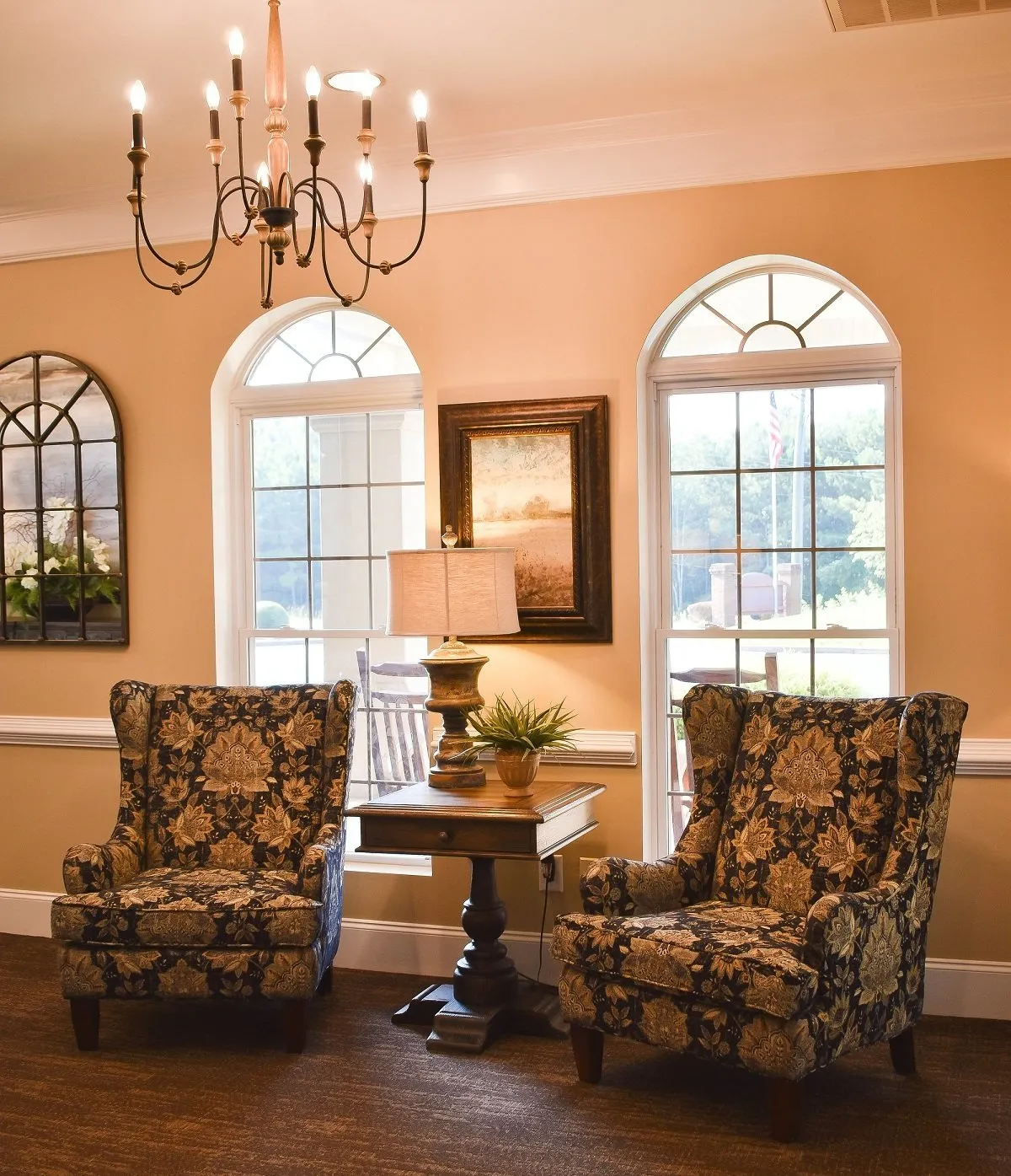 A living room with two chairs a table and a chandelier