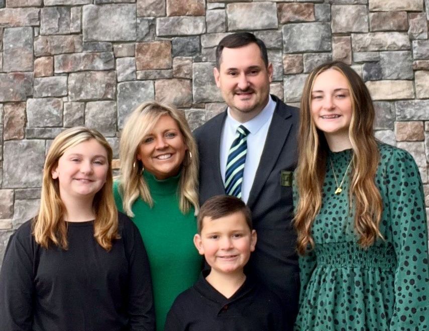 A family posing for a picture in front of a stone wall.