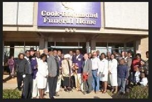 Group of people outside Cook-Richmond Funeral Home. Building has purple sign.