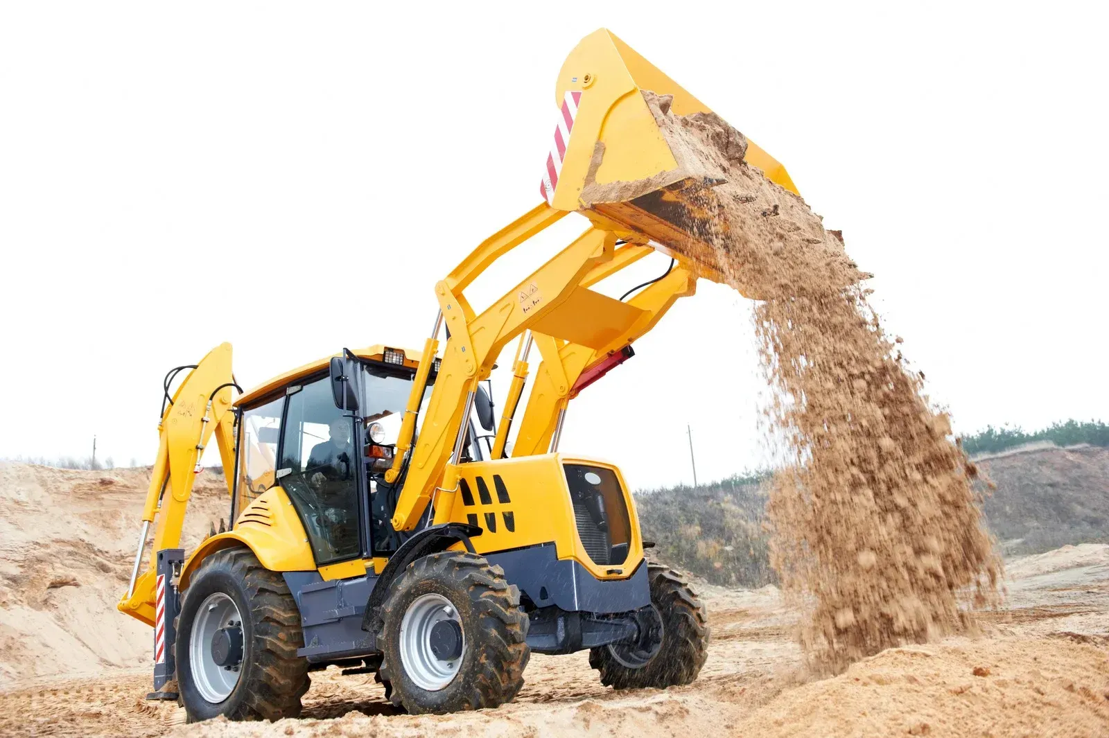 A yellow bulldozer is pouring dirt into a pile on a construction site.