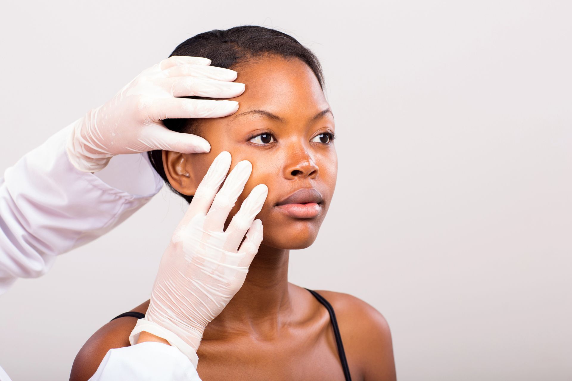 A woman is getting her face examined by a doctor.