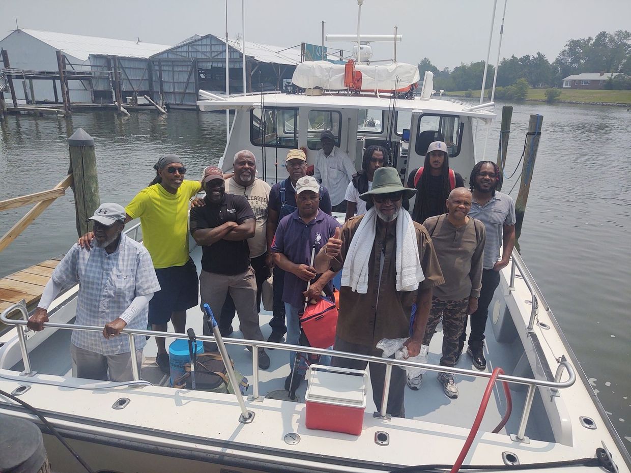 A group of men are standing on a boat in the water.