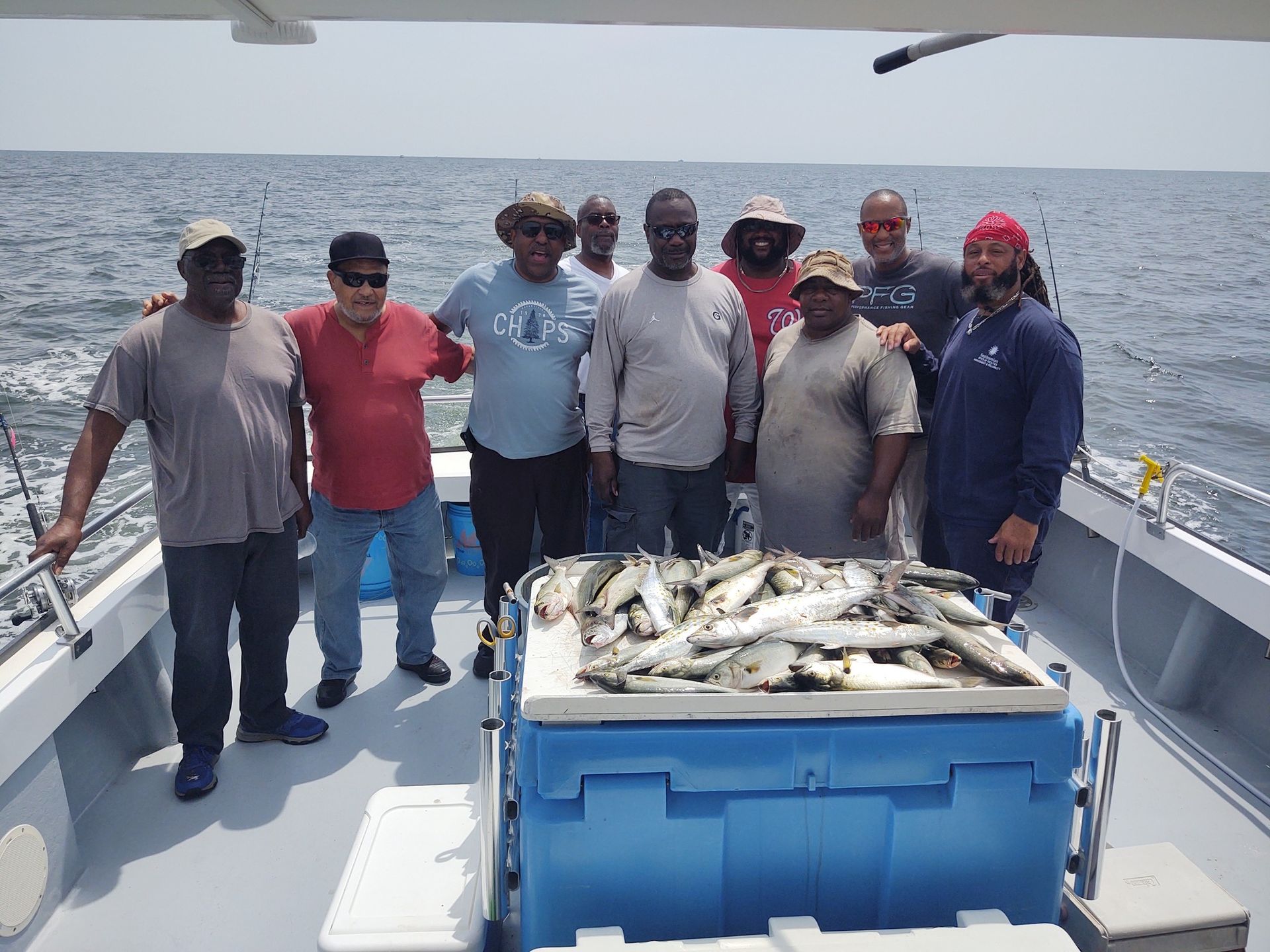 A group of men are posing for a picture on a boat filled with fish.