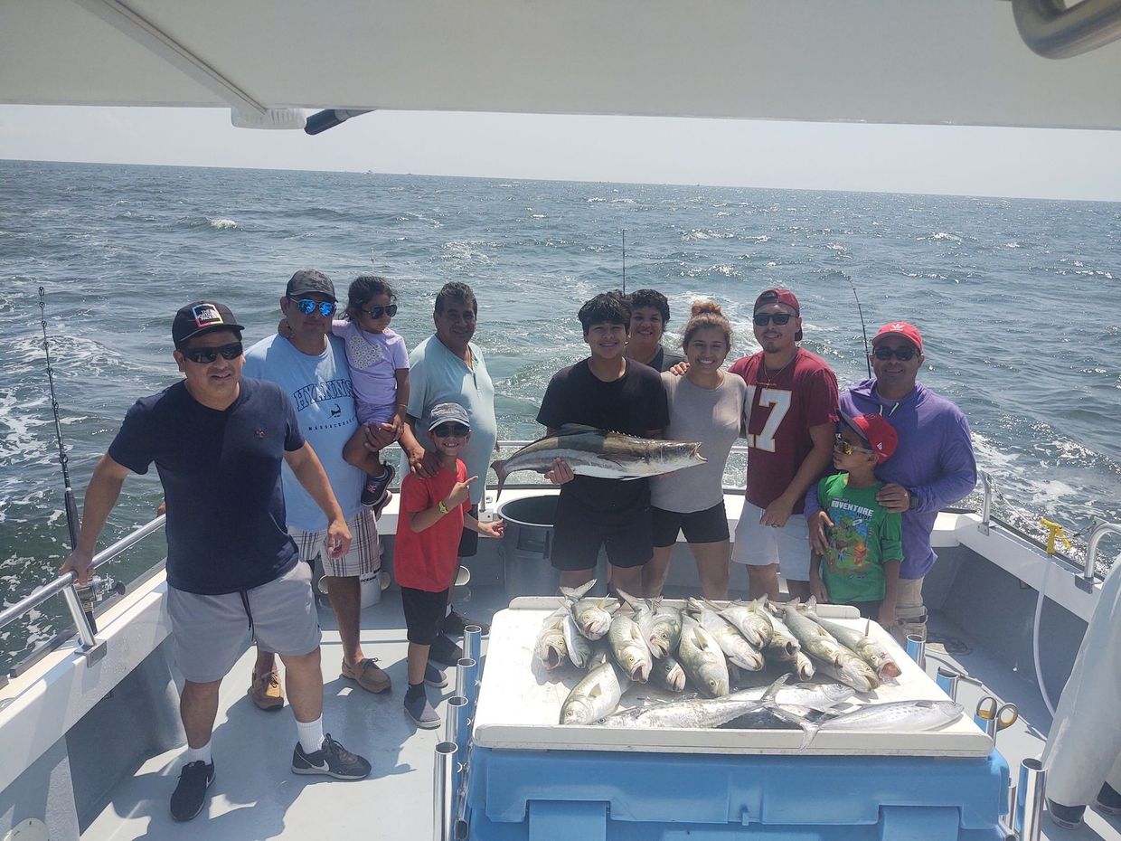 A group of people are standing on a boat holding fish.