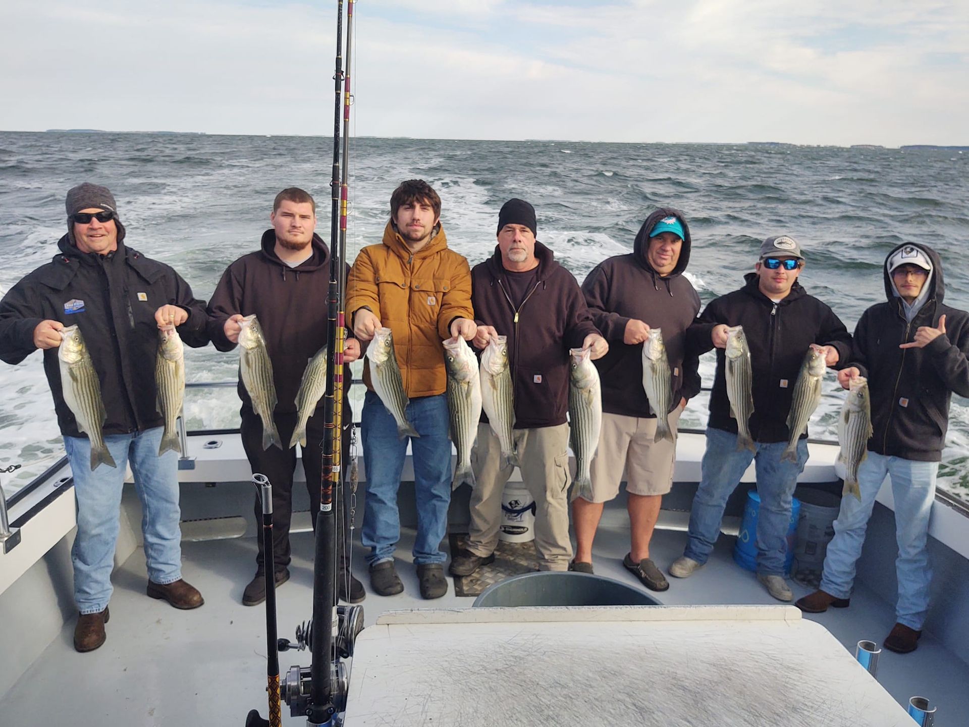 A group of men are standing on a boat holding fish.