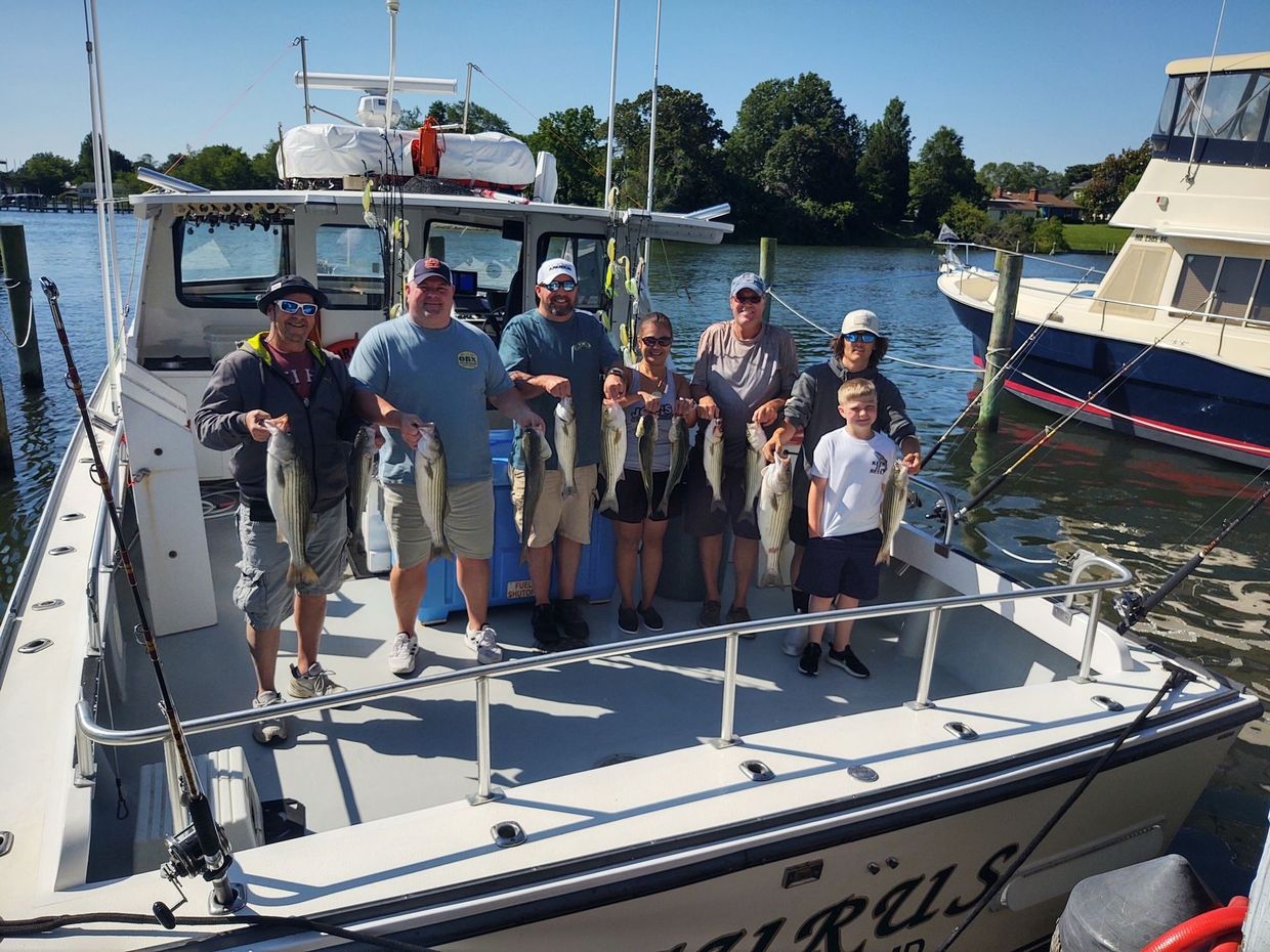 A group of people are standing on a boat holding fish.