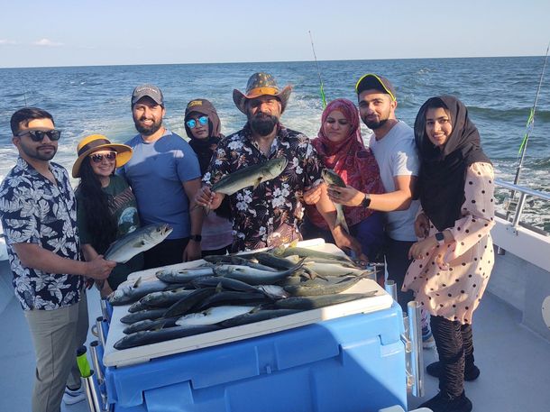 A group of people are standing on a boat holding fish.
