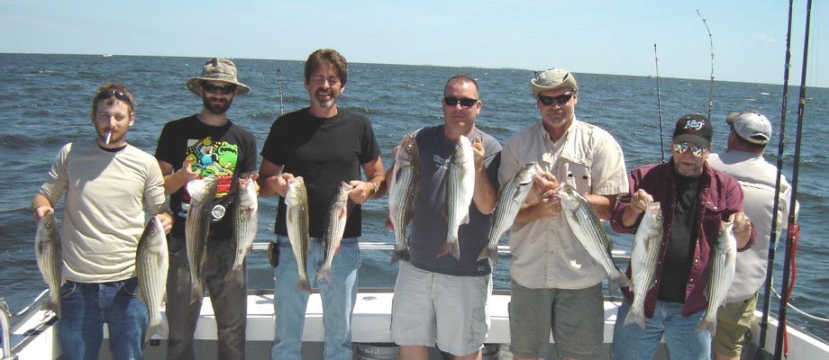 A group of men standing on a boat holding fish