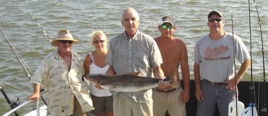 A group of people standing on a boat holding a large fish