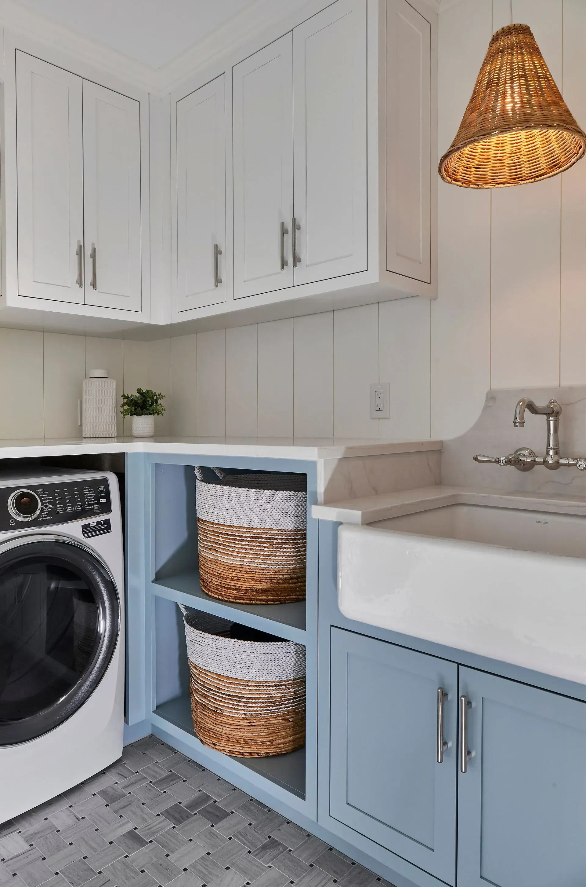 Laundry room with white upper cabinets, blue lower cabinets, and woven pendant light.