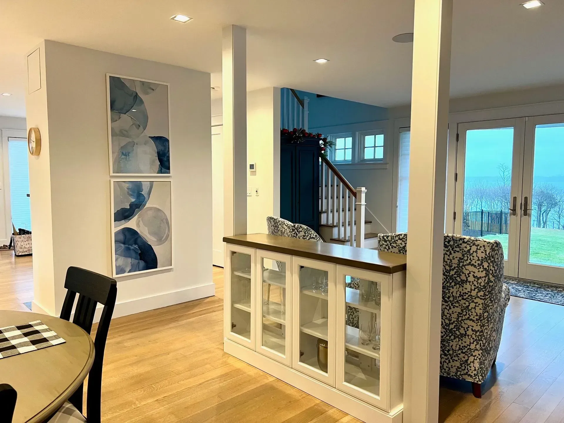 Living room interior with hardwood floors, artwork, and a white and wood-toned cabinet.