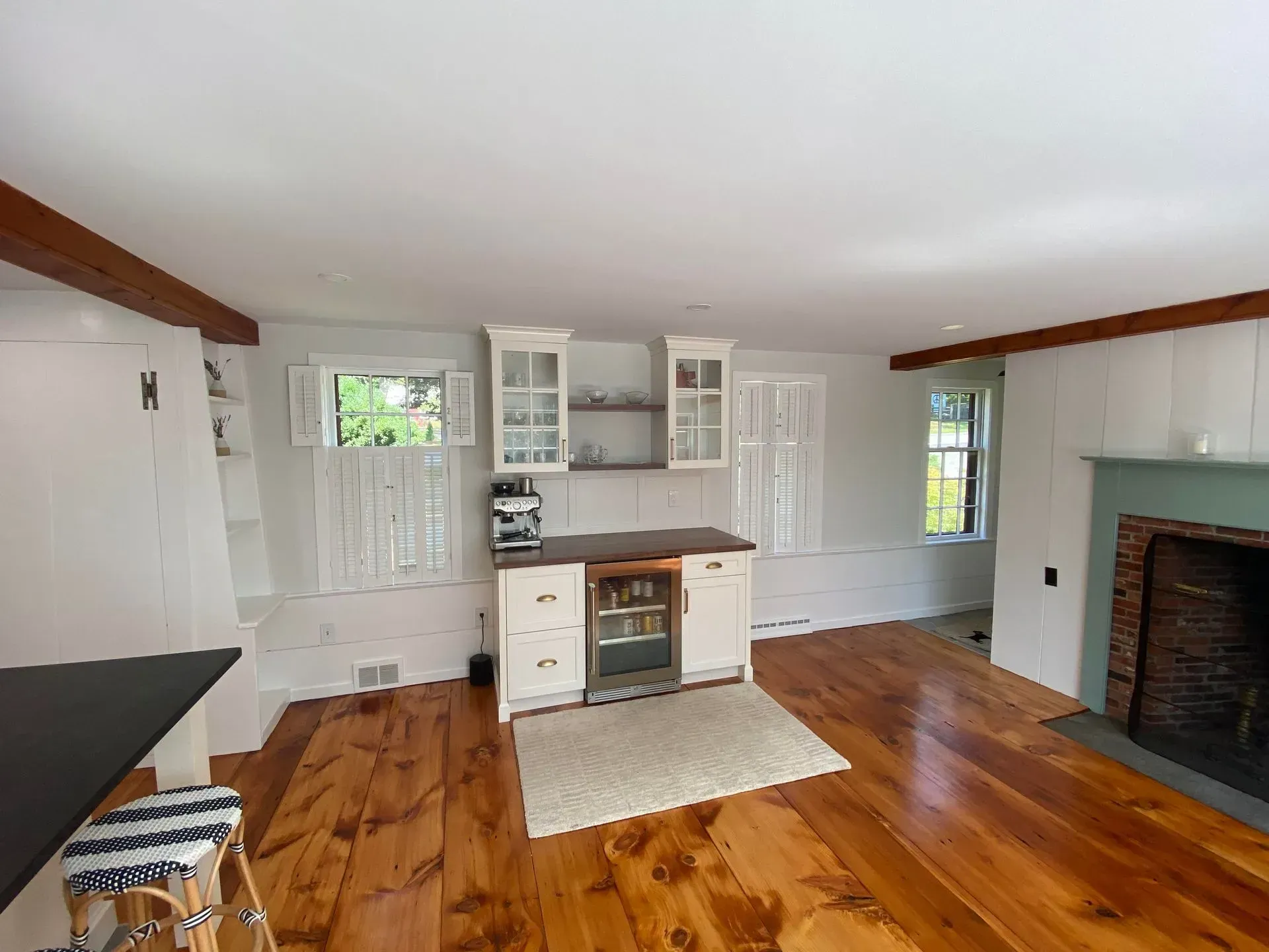 Kitchen with white cabinets, wooden floor, and a brick fireplace.
