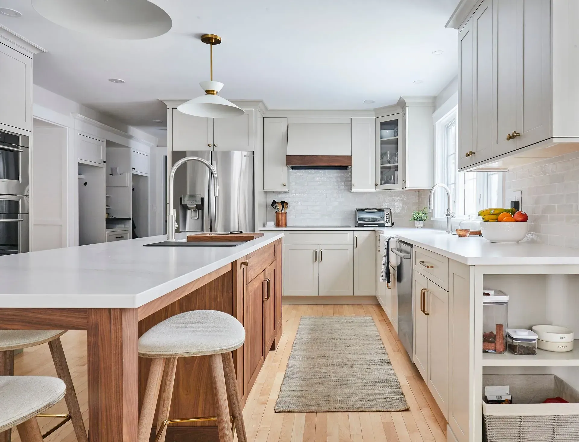 Modern kitchen with white cabinets, wood island, stainless steel appliances, and light wood floors.