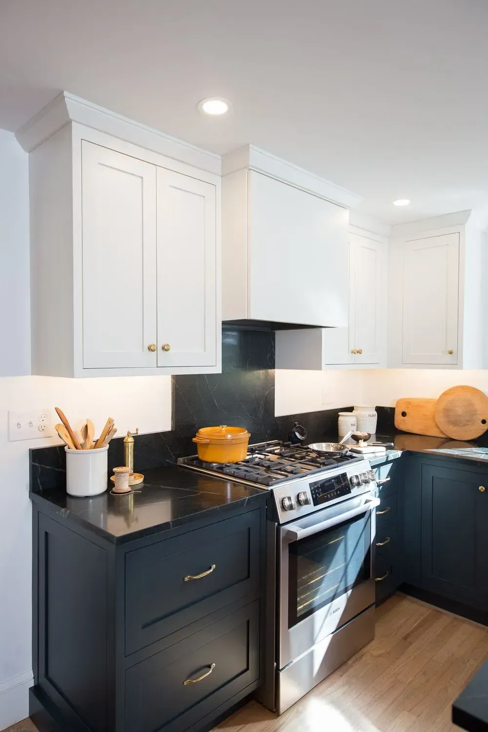 Kitchen with white upper cabinets, dark blue lower cabinets, and stainless steel oven.