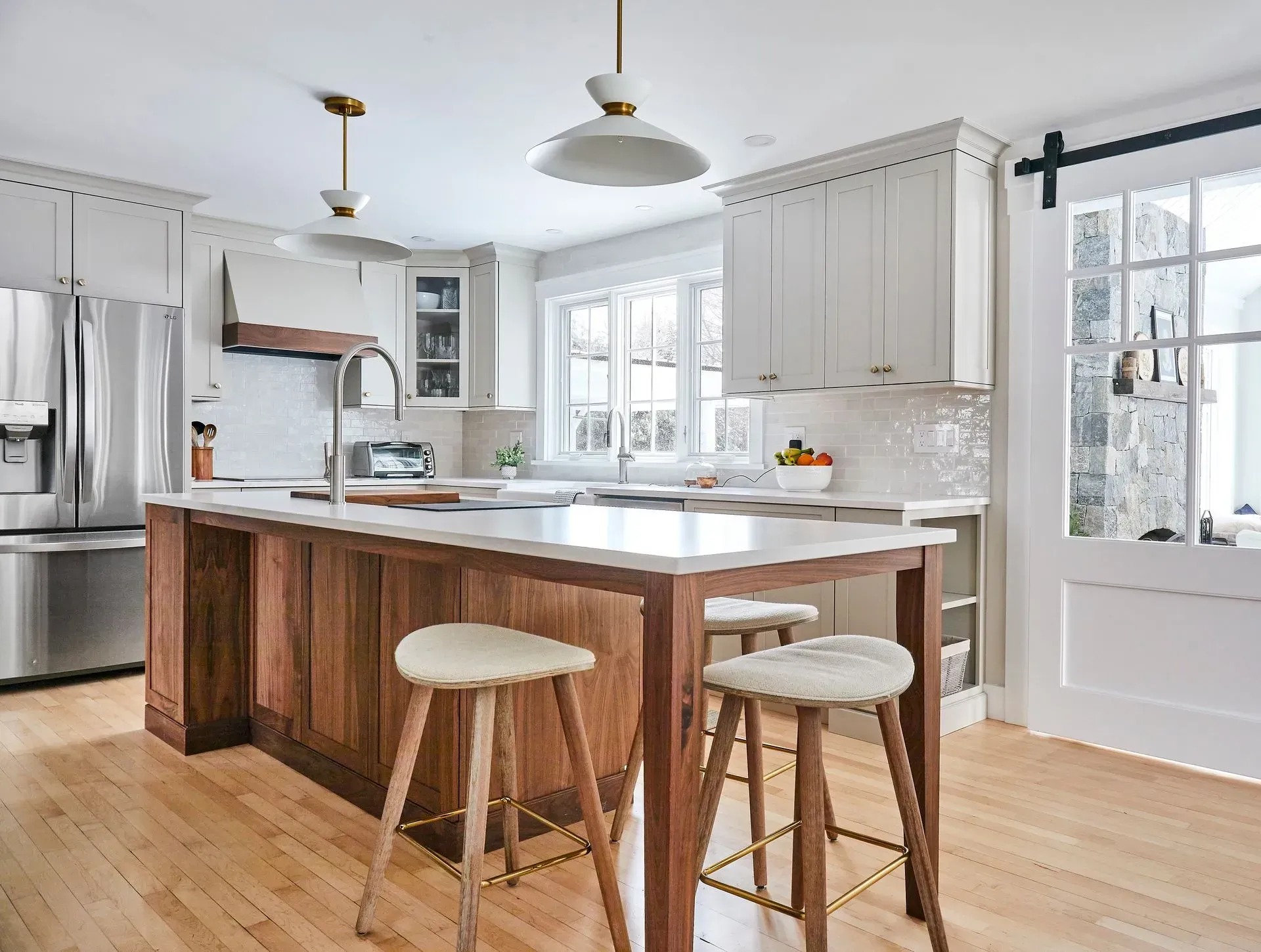 Modern kitchen with wood island, white cabinets, and stools.