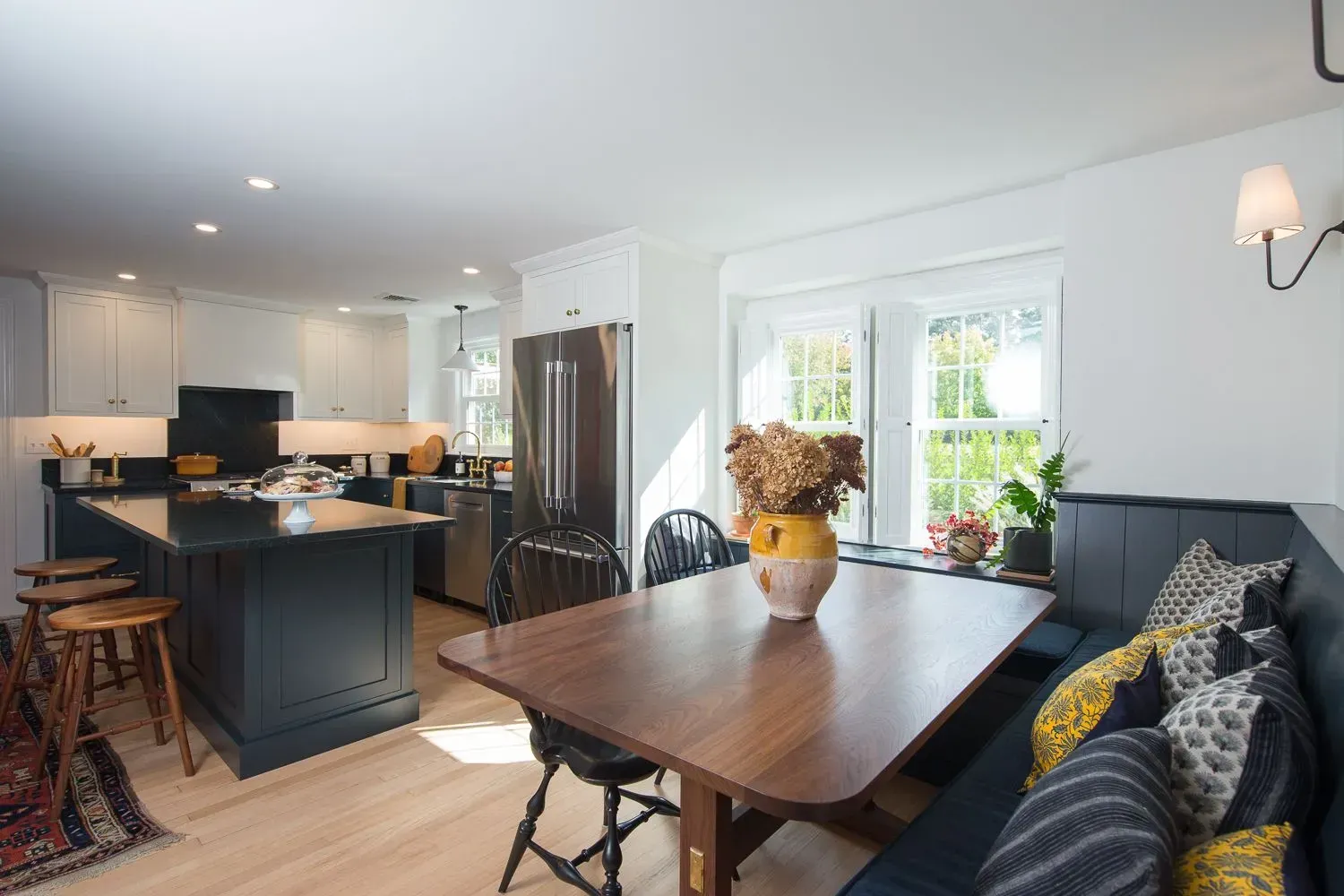 Modern kitchen with navy island, stainless steel appliances, and built-in dining nook.