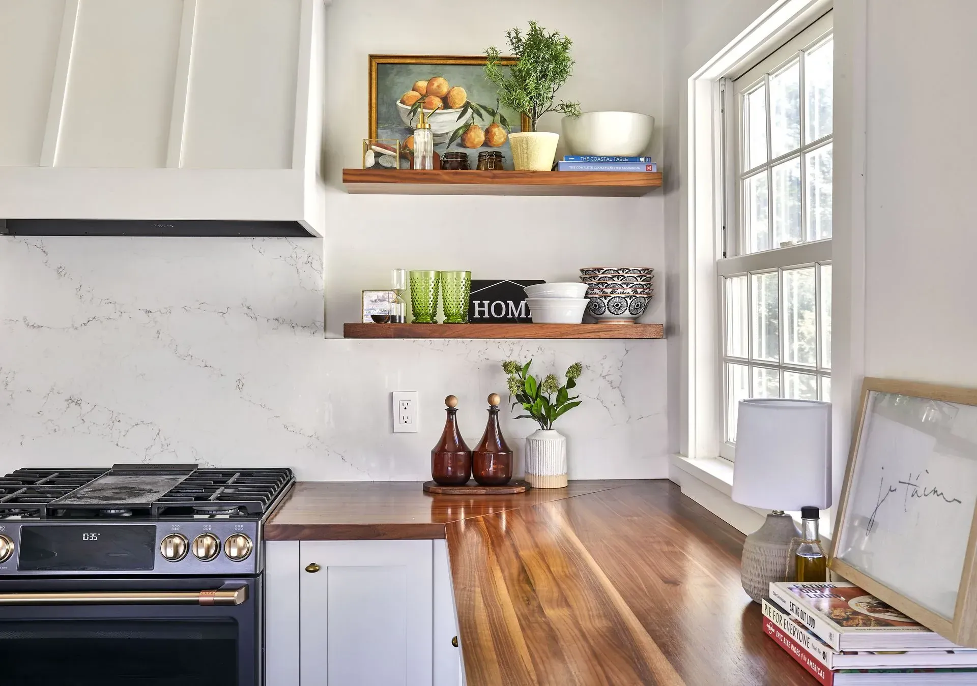 Kitchen with wooden countertops, white cabinets, marble backsplash, floating shelves with decor, and a window.