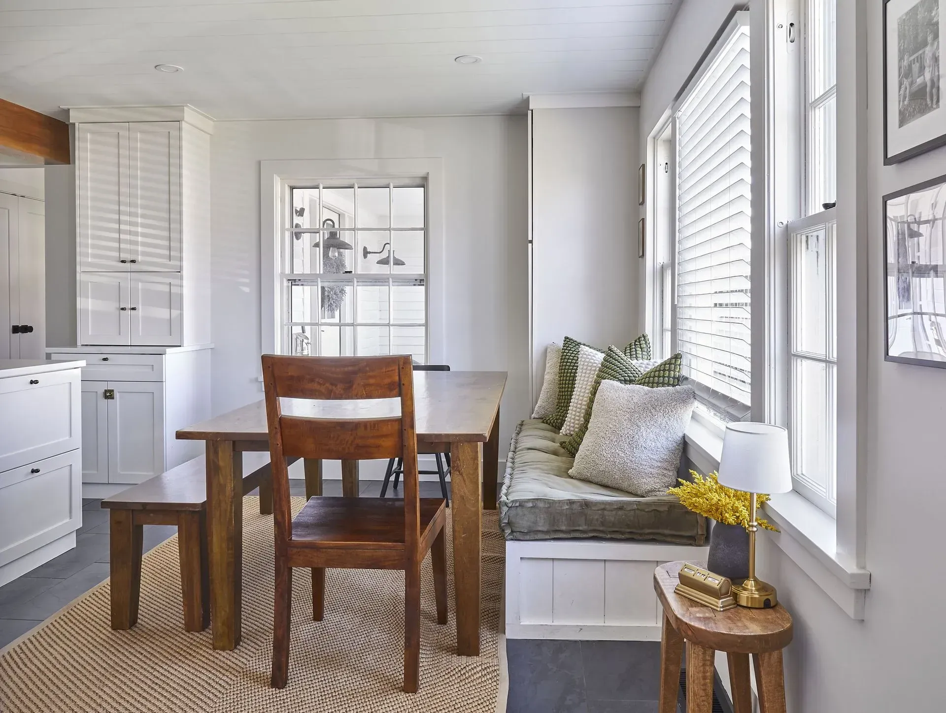 Dining area with wooden table, bench, chair, built-in window seat, and neutral color palette.