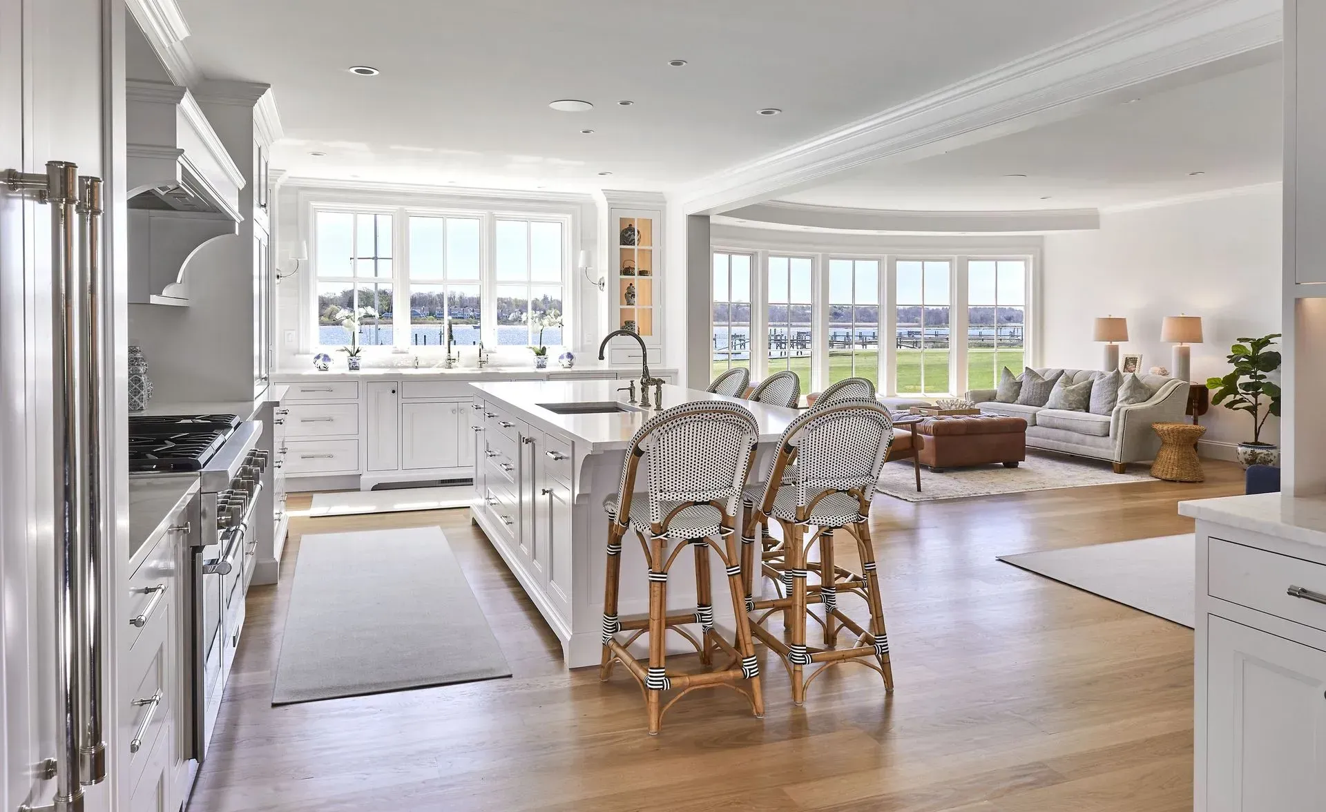 White kitchen with island, zebra-print bar stools, and open view to living area with lake.