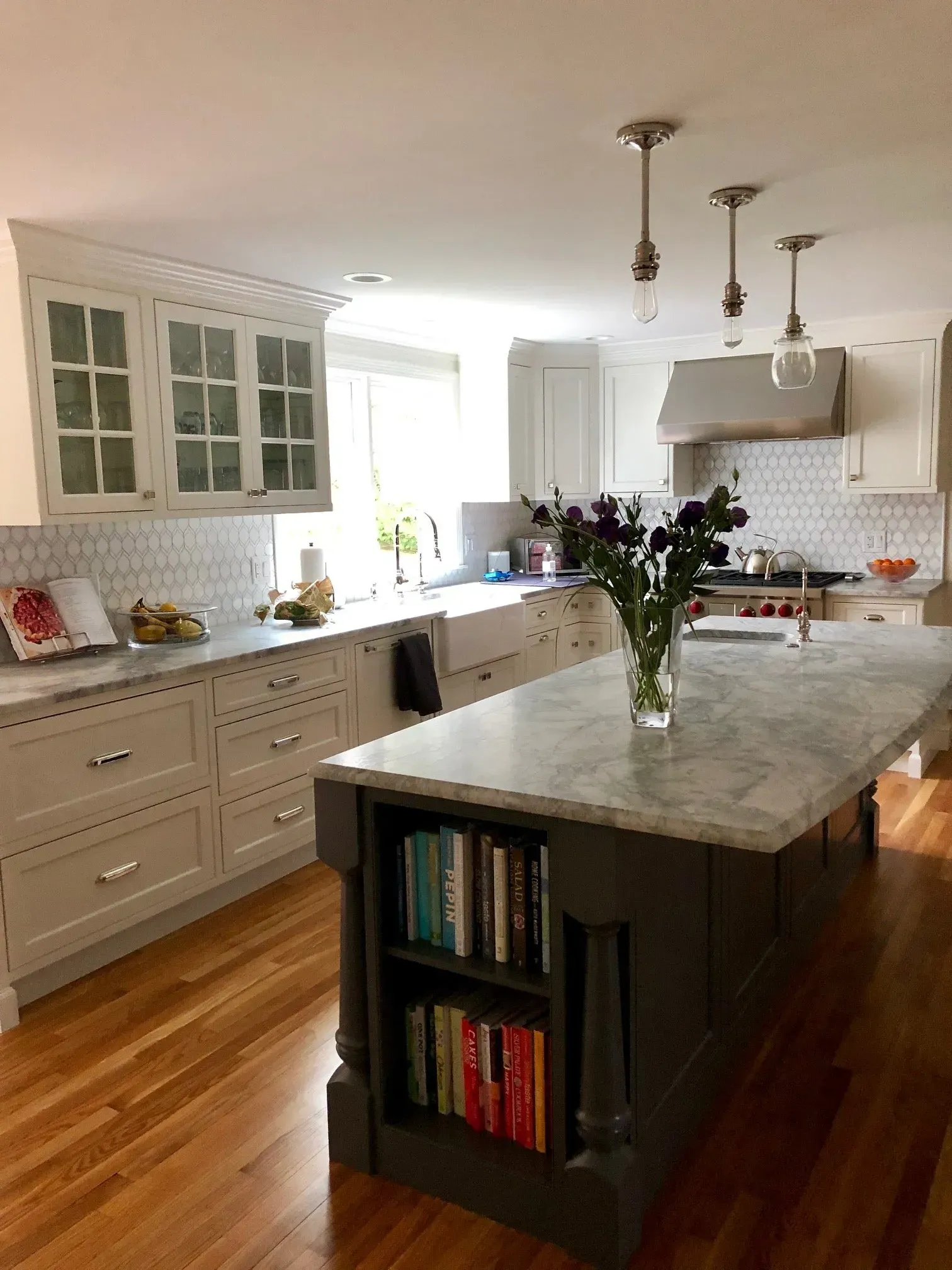 A bright, spacious kitchen with a large island, white cabinets, marble countertops, and hardwood floors.
