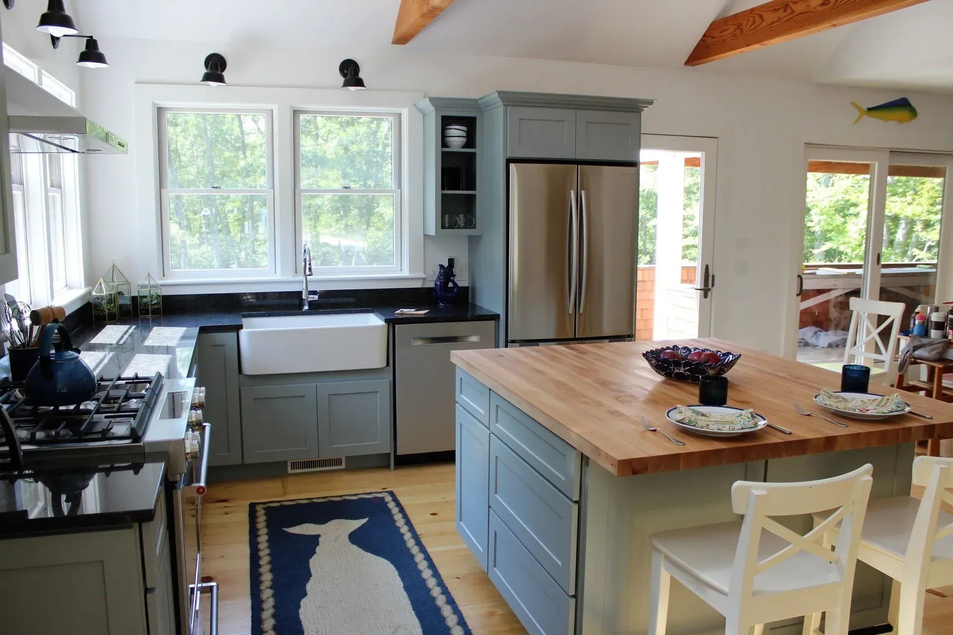 Coastal-style kitchen with blue cabinets, stainless steel appliances, and a butcher block island.