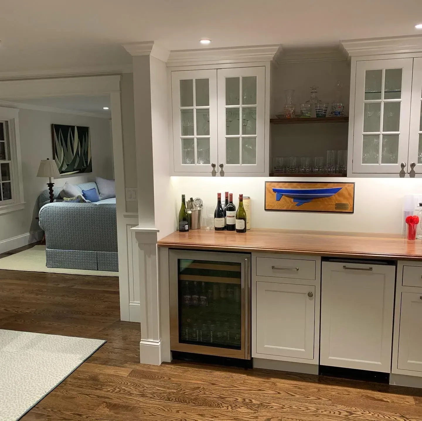 Kitchen with white cabinets, copper countertop, and wine refrigerator; view into a bedroom.