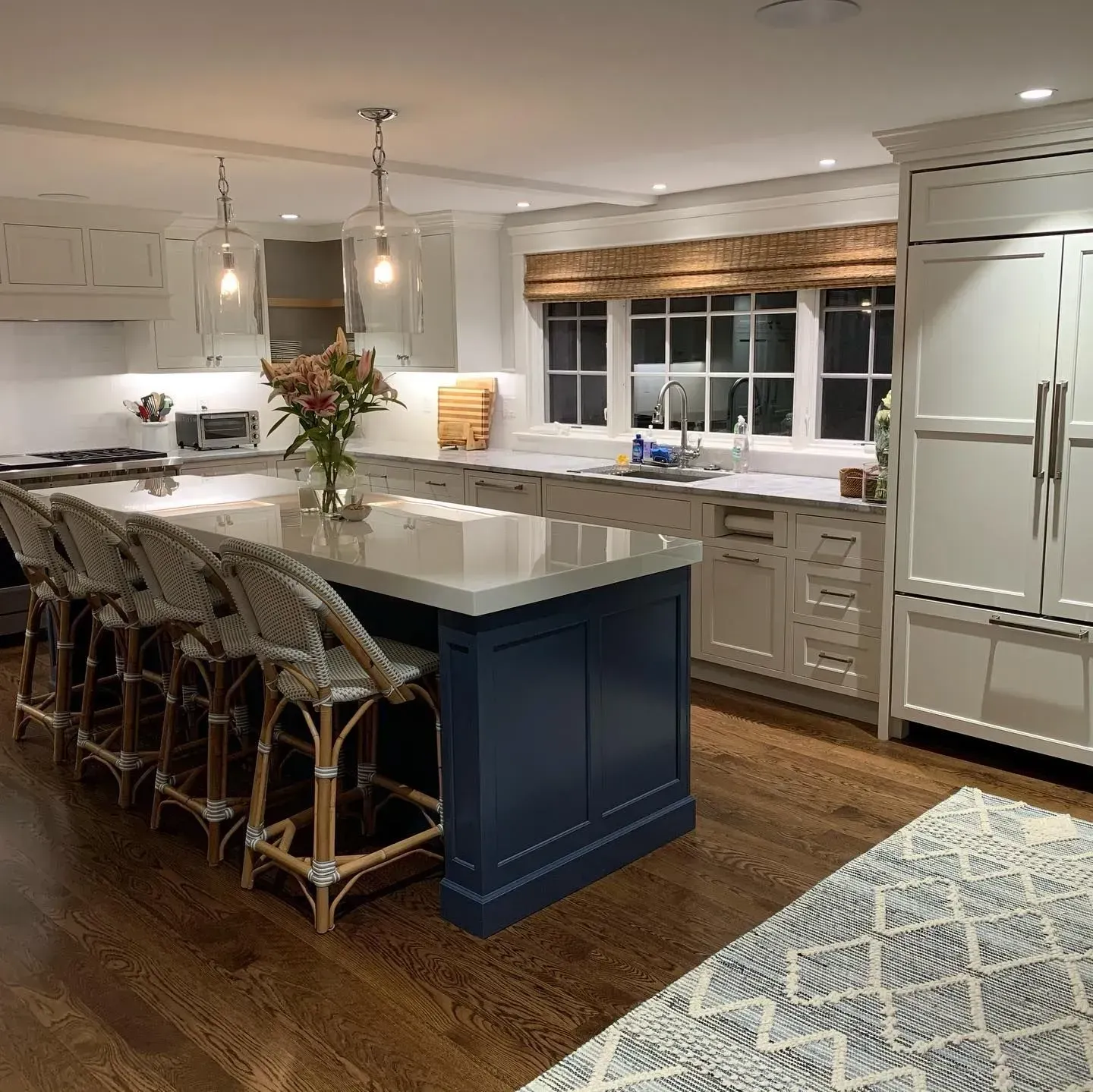 Kitchen with blue island, light gray cabinets, and dark wood floors.