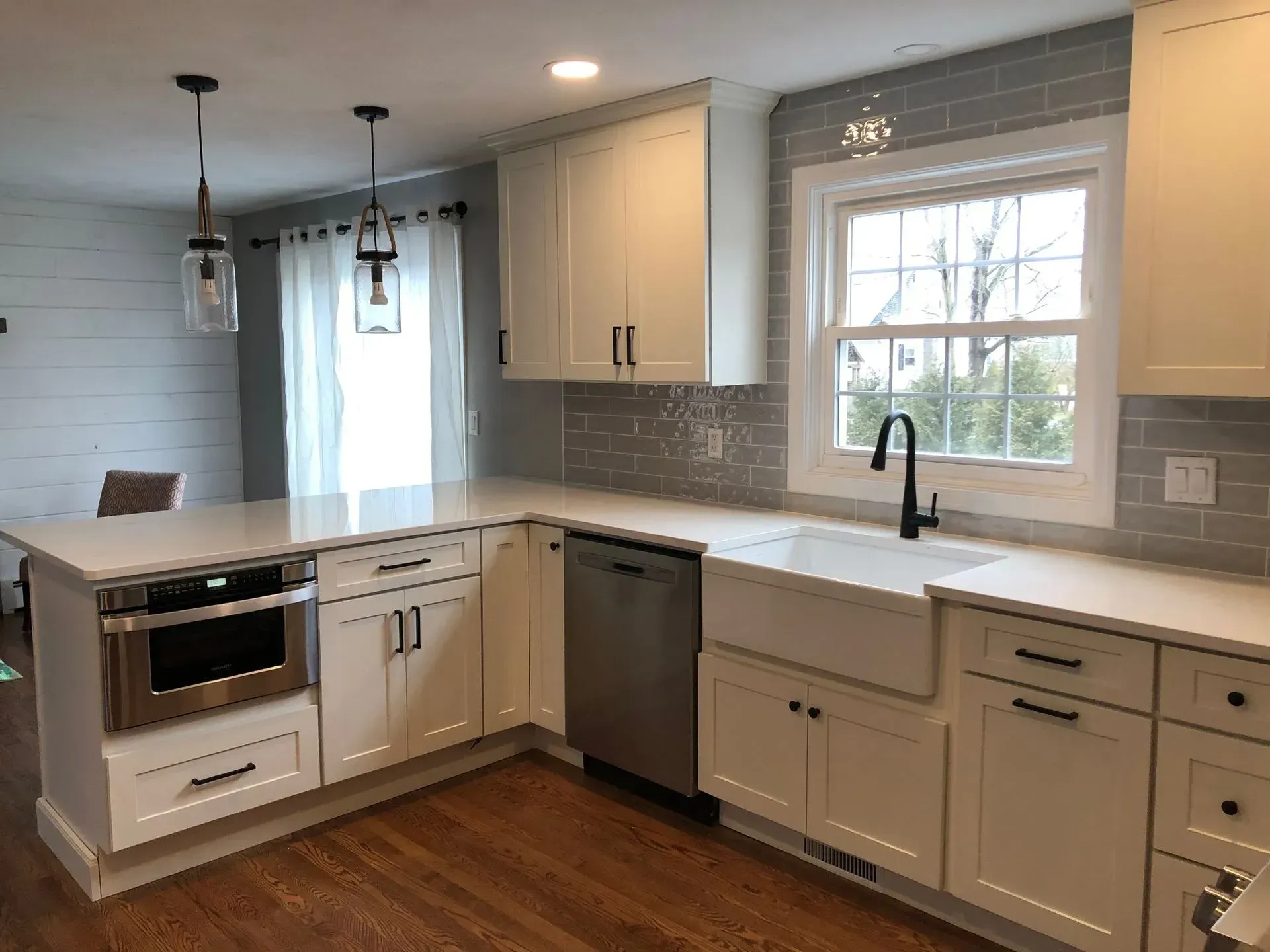 Modern white kitchen with stainless steel appliances, white cabinets, and a white countertop.