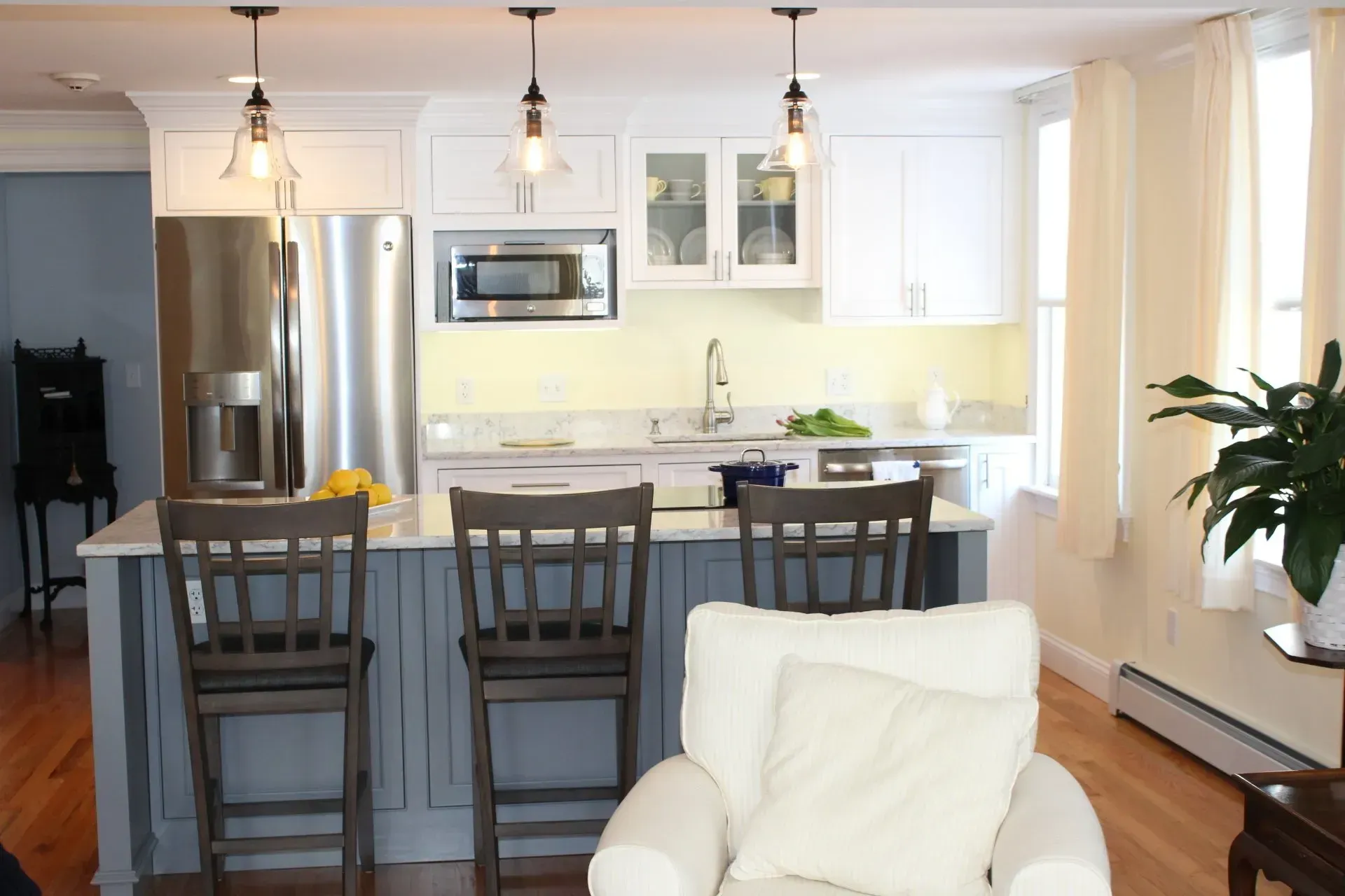 Modern kitchen with island, white cabinets, stainless steel appliances, and pendant lights.