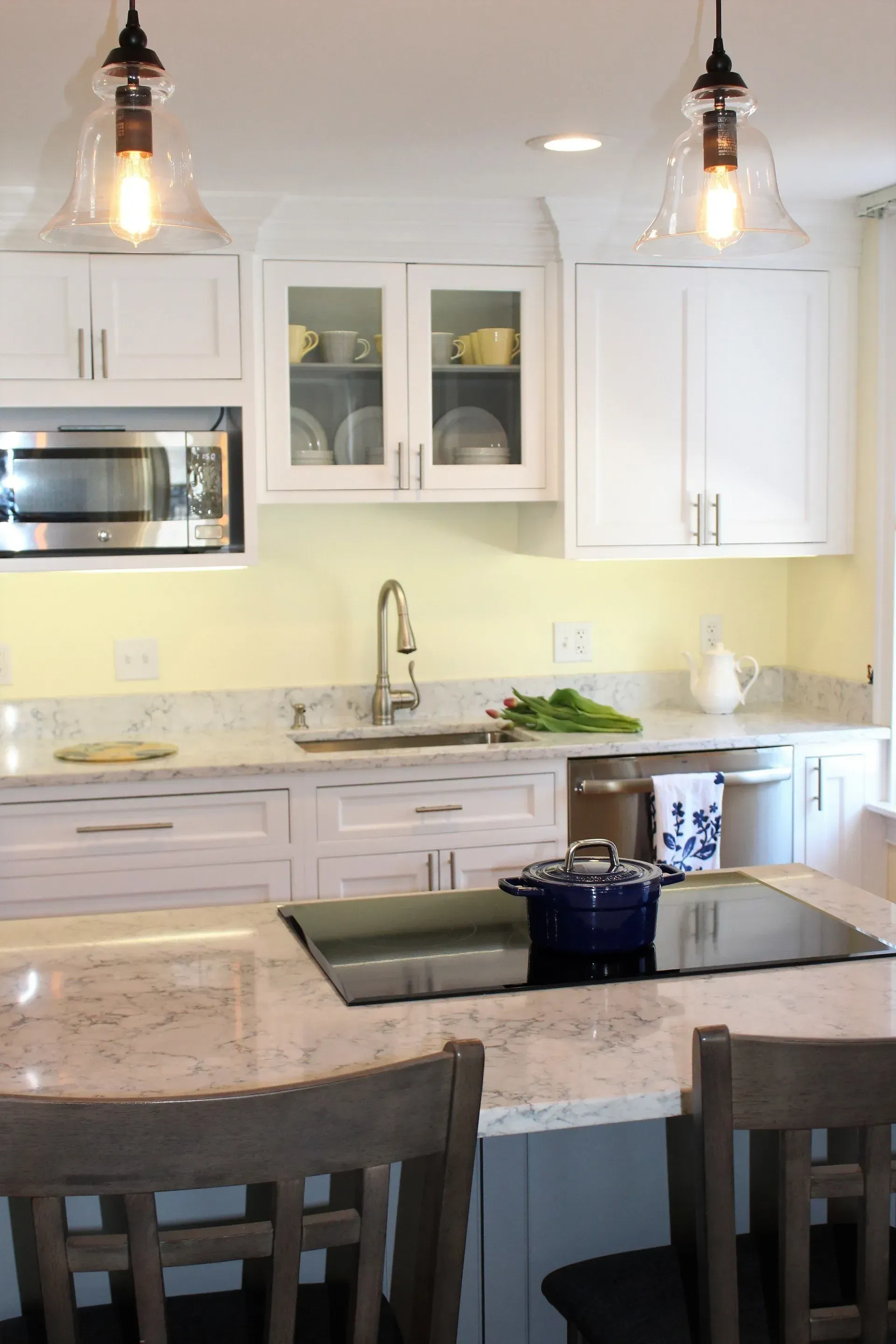 Kitchen with white cabinets, granite countertops, and two pendant lights. A blue pot sits on the stovetop.