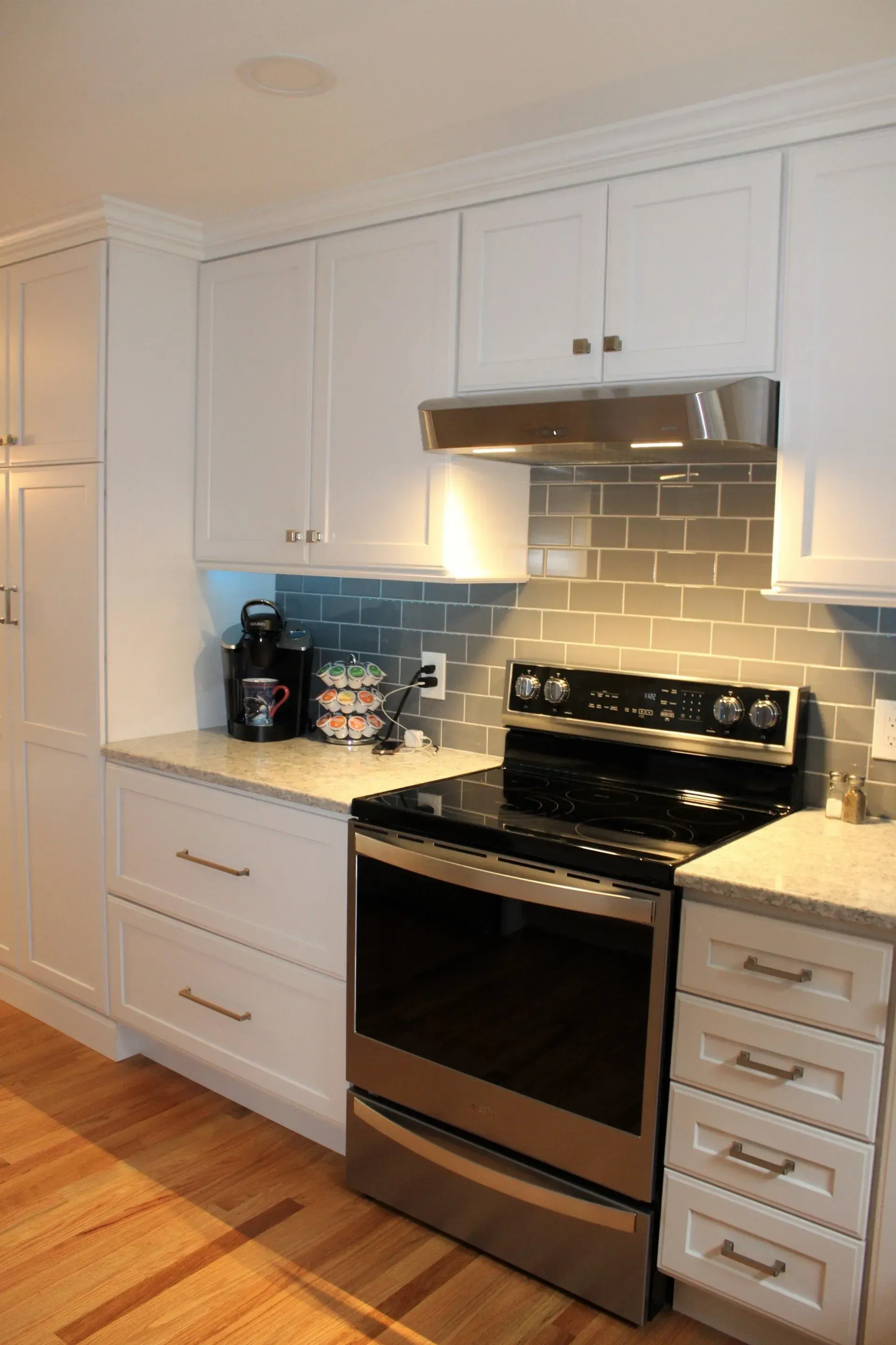 Kitchen with white cabinets, stainless steel appliances, and gray tile backsplash.