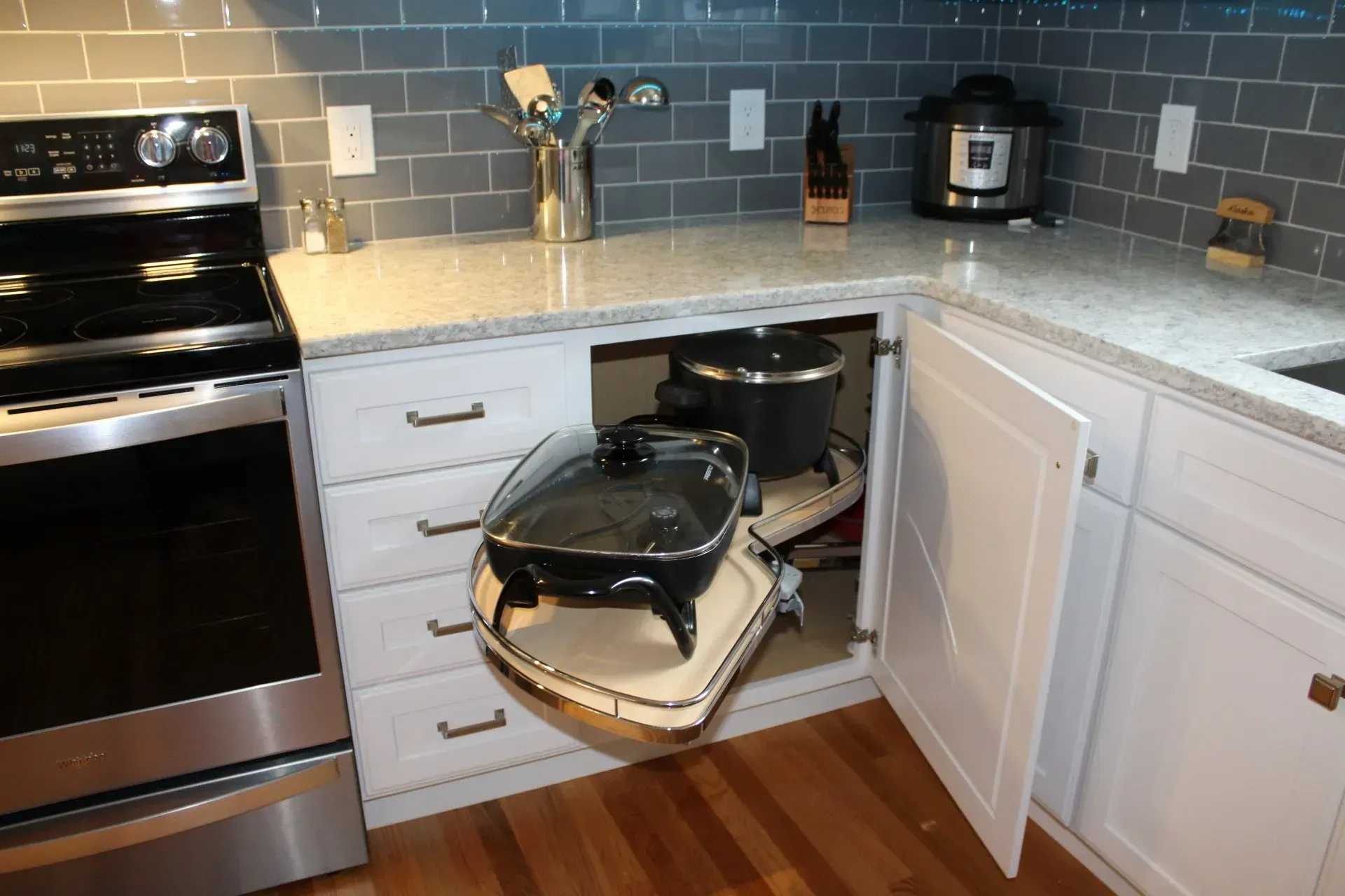 Kitchen cabinet with pull-out corner shelves, holding appliances; electric griddle and slow cooker.