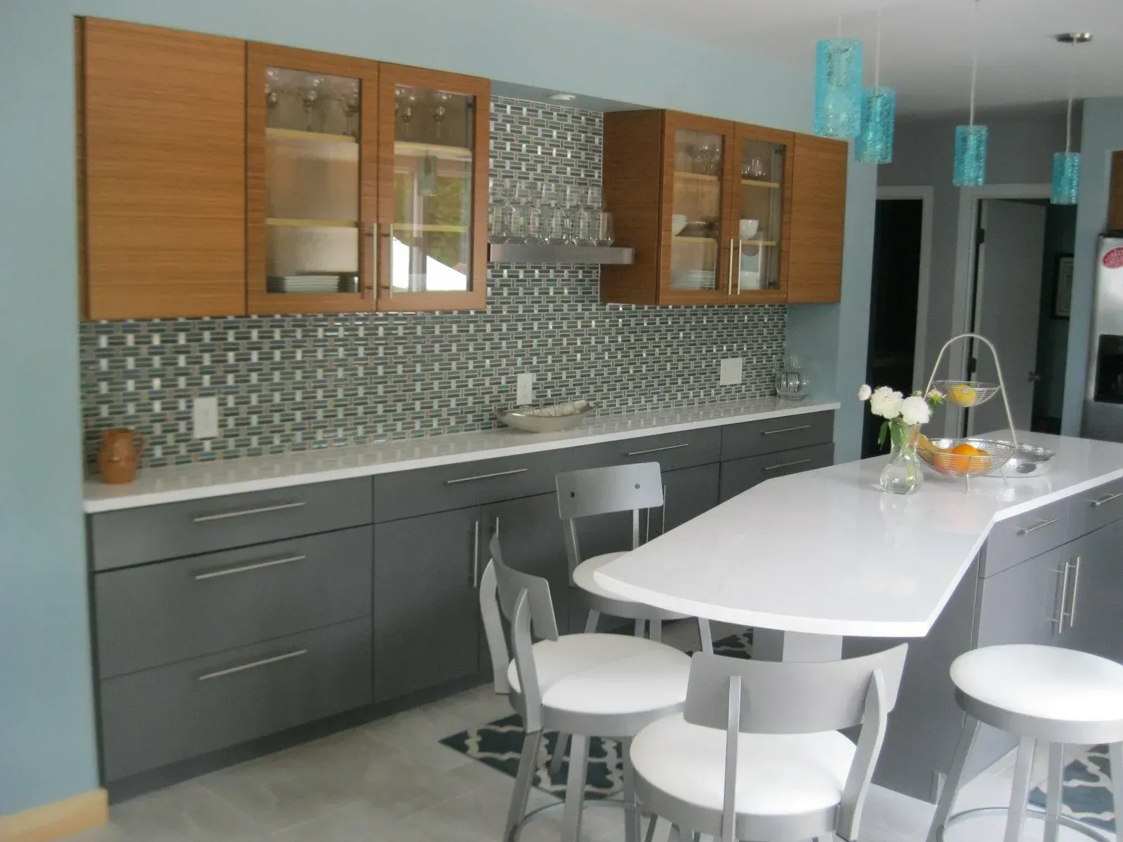 Modern kitchen with gray cabinets, white countertop, and blue mosaic backsplash.