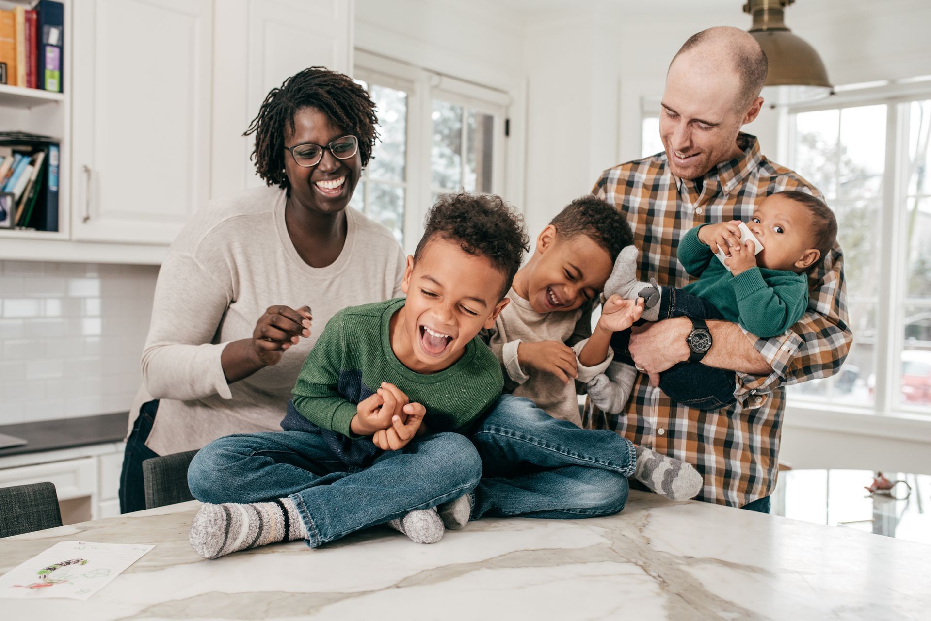 A family is sitting on a counter in a kitchen.