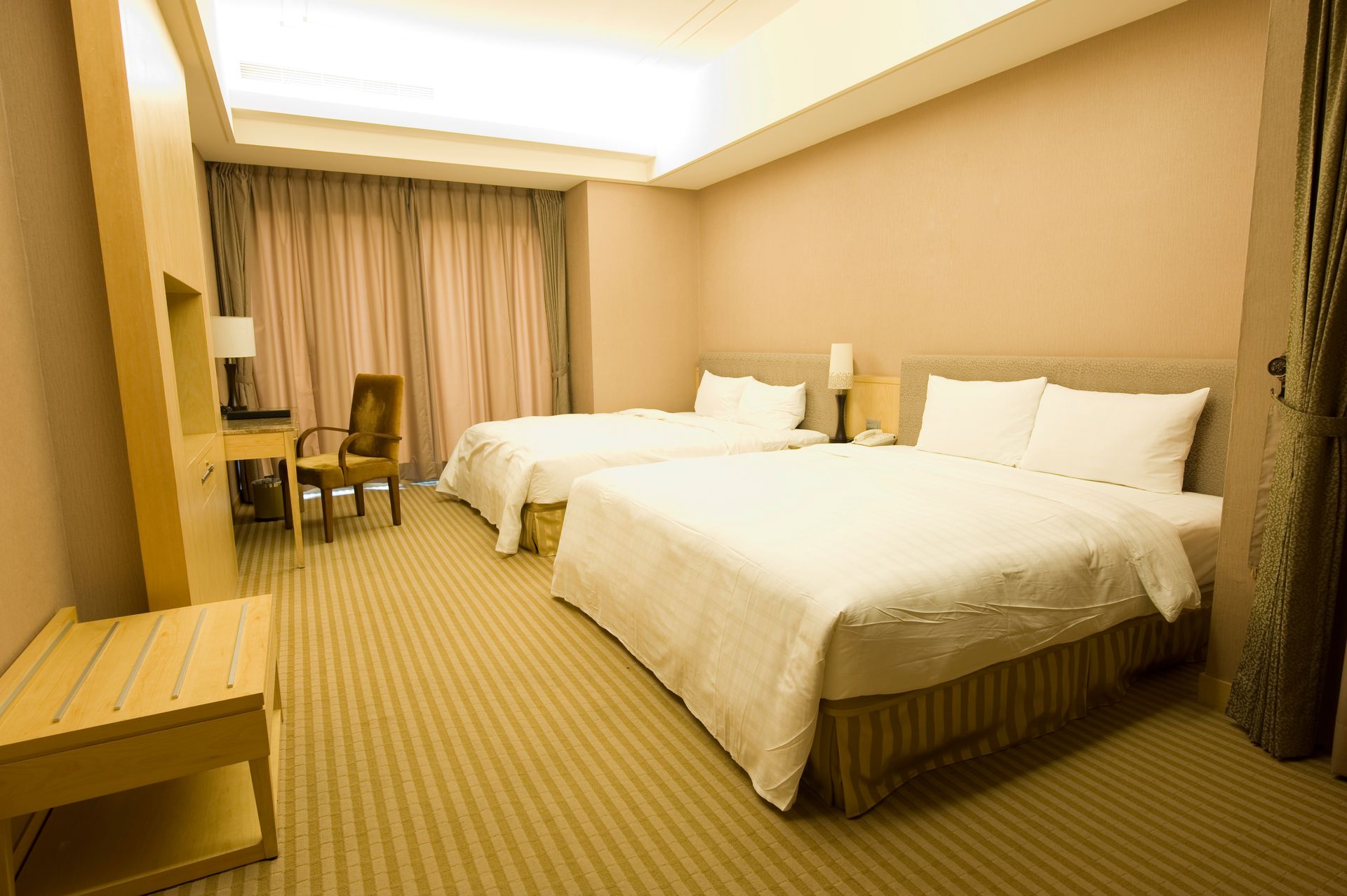 A hotel room with two beds , a chair and a desk.