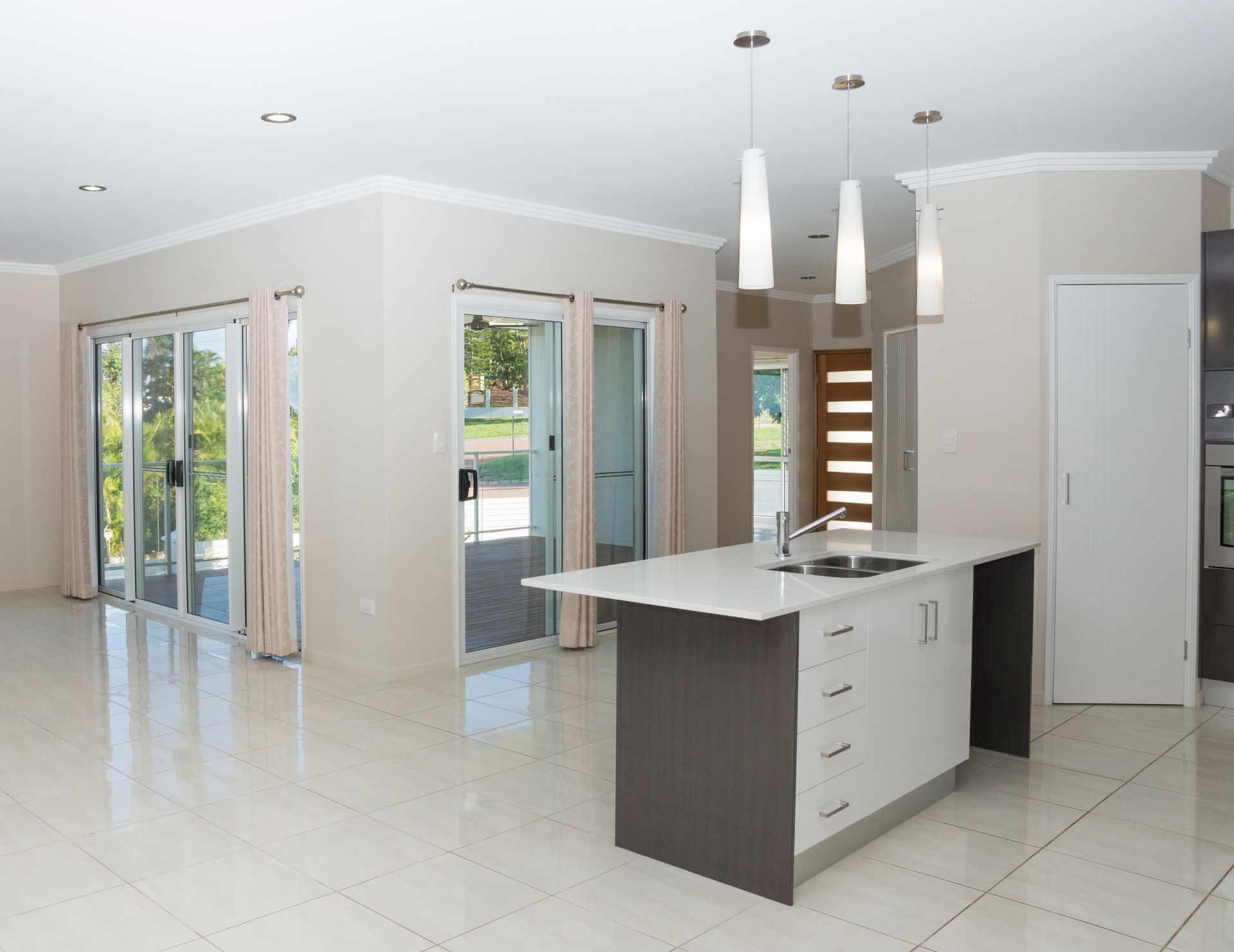 An empty kitchen with a large island and sliding glass doors