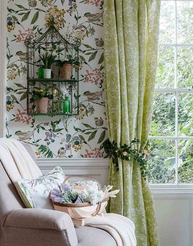 A chair and window in a room decorated with floral design