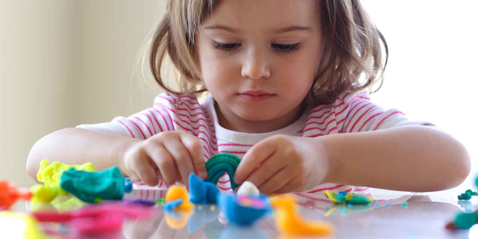 Developing Fine Motor Skills: A little girl playing with Play Dogh To Improve Motor Skills