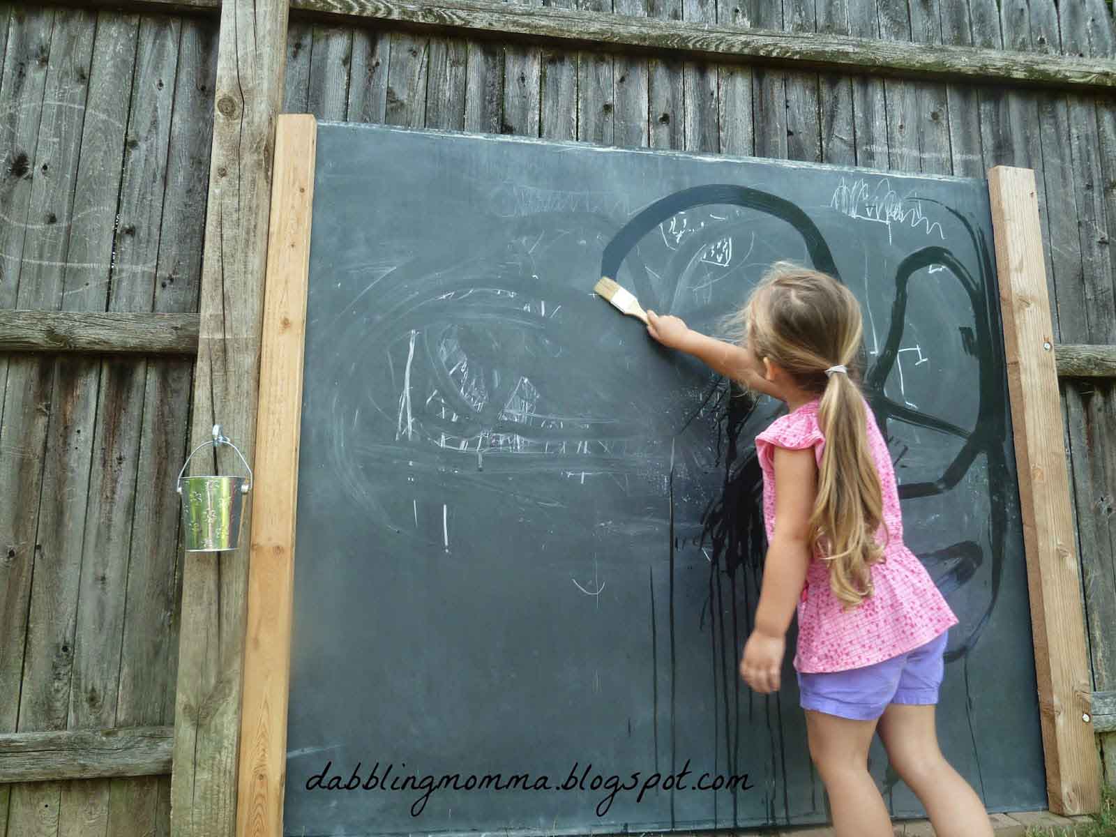 Developing Fine Motor Skills: A girl us a paint brush on a chalk board to improve motor skills