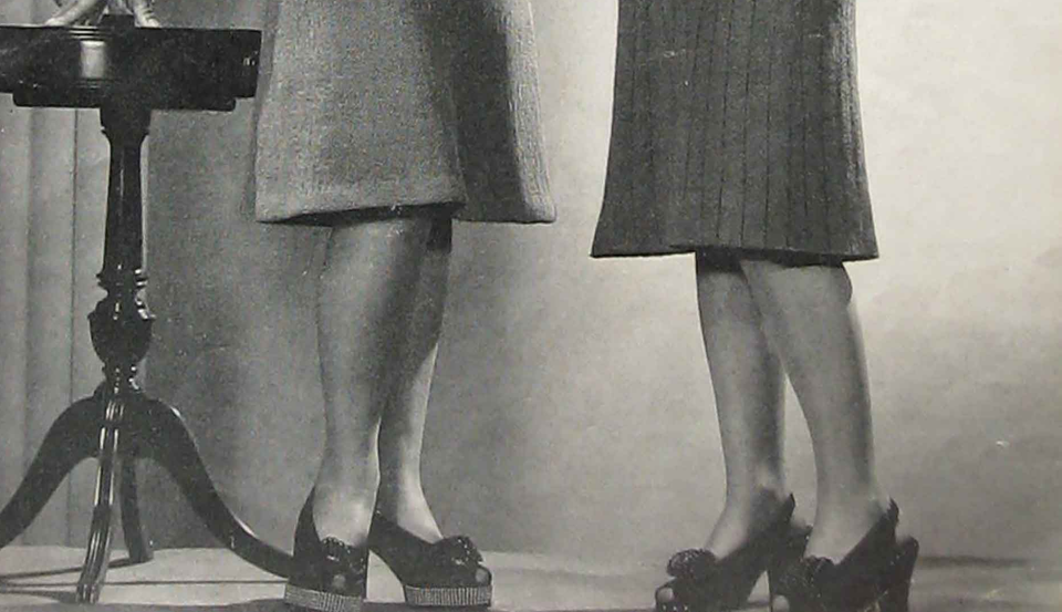 Legs of two women wearing platform shoes and skirts.