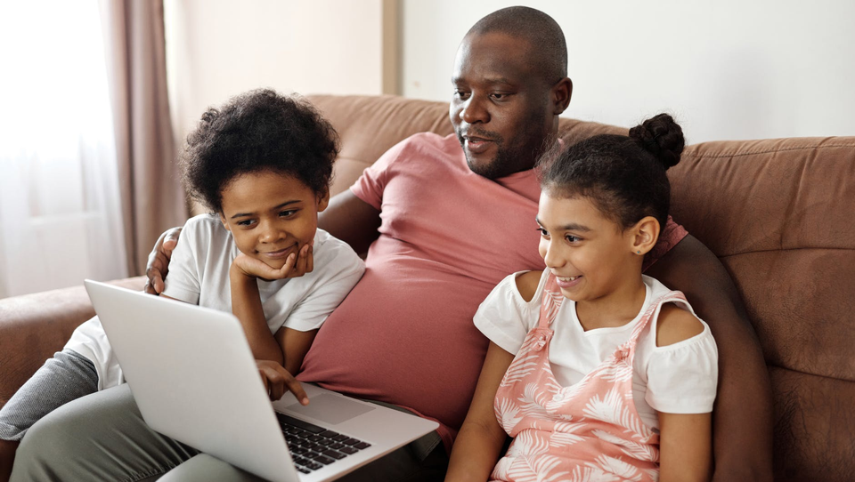 Father and children sat together looking at a laptop